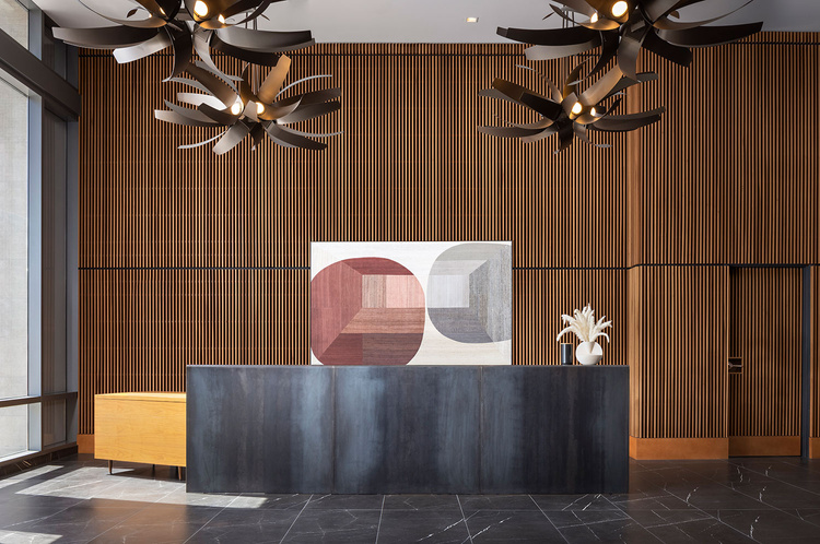 the lobby of a modern apartment building with wood paneling and a large art piece on the wall reception desk